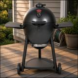 Graphite Char-Griller AKORN kamado on its wheeled frame with two side shelves, on a timber deck