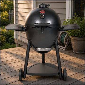 Graphite Char-Griller AKORN kamado on its wheeled frame with two side shelves, on a timber deck