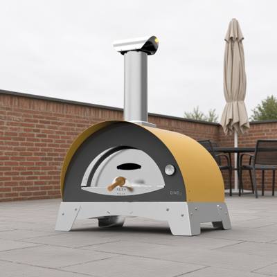 Alfa Ciao wood fired oven in yellow on paving beside a brick wall, a parasol and chairs behind
