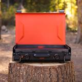 Blackstone 20 inch camping griddle open on a tree stump, front panel with two knobs and a center carry handle