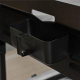 Close view of the black rear grease cup hanging in its bracket below the drain slot at the back of the griddle