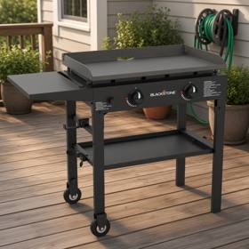 Blackstone 1517 28 inch griddle with its side shelf out, on a timber deck beside a house