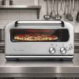Breville Smart Oven Pizzaiolo in brushed stainless on a kitchen bench, a pizza baking inside