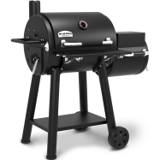 Broil King Regal 400 Charcoal Offset, black steel barrel cooker with a smaller offset chamber at right and two wheels.