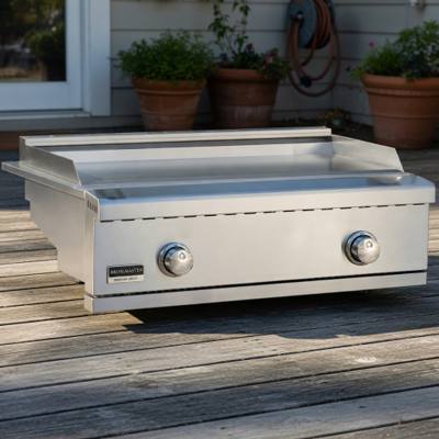 Broilmaster stainless griddle head on a weathered deck, bare flat plate with rear backsplash, two round front knobs