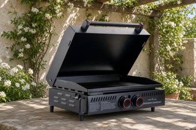 Black Camp Chef Gridiron Gameday griddle with its hinged lid raised over the flat top, two red-ringed knobs in front