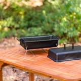 Char-Broil 190 portable charcoal grill on a wooden garden table, bare grate, its lid lifted off alongside