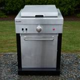 Char-Broil Medallion griddle module on gravel beside a lawn, stainless cabinet, lid closed, black corner posts