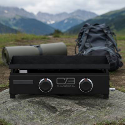 Char-Broil 22-inch tabletop gas griddle on a rock outdoors, black body, two control knobs, mountains behind