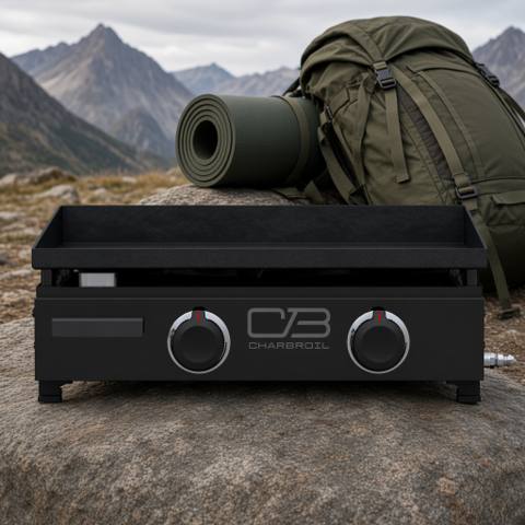 Char-Broil 22-inch tabletop gas griddle on a rock outdoors, black body, two control knobs, mountains behind