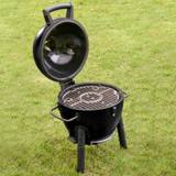 AKORN Jr. on a lawn with the lid swung open, showing the round cast iron grate inside the black bowl