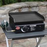 Flat Iron Portable griddle on a folding aluminium camp table outdoors, green propane cylinder hooked to its hose