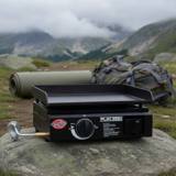 Black Char-Griller Flat Iron portable griddle on a rock at a misty mountain camp, single knob, hose fitted