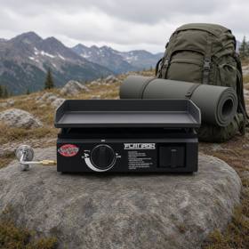 Black Char-Griller Flat Iron portable griddle on a rock at a misty mountain camp, single knob, hose fitted