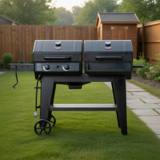 Char-Griller FlexFuel Plus on a mown lawn, twin black lids closed, two gas knobs, side shelf and wheels