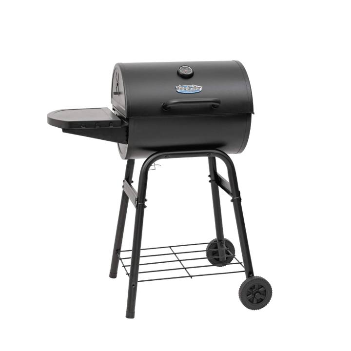 King-Griller Gambler E1416 barrel charcoal grill on its four-leg cart, lid shut, side shelf out, on a stone terrace