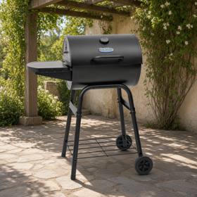 King-Griller Gambler E1416 barrel charcoal grill on its four-leg cart, lid shut, side shelf out, on a stone terrace