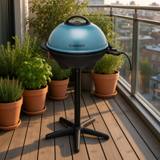 Cuisinart CEG-1149 with its teal domed lid closed, on the black pedestal stand, control probe and cord at right