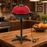 Cuisinart CEG-115 electric grill with red domed lid closed, on its black five-leg pedestal stand, cord trailing