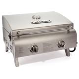 Cuisinart CGG-306P stainless tabletop gas grill, lid closed, standing on a rock outdoors with a backpack behind it