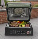 Cuisinart FlavorBoost CEG-1302 with its green lid open, steak and vegetables on the grill plate, panel lit