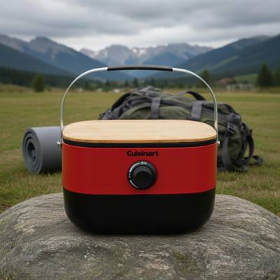 Cuisinart Venture portable grill closed on a rock, red body with its wooden board on top and carry handle raised