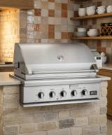 DCS 36-inch stainless steel built-in gas grill set into a stone outdoor kitchen counter, hood closed