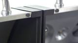Close-up of the seam between the Dyna-Glo dual fuel grill's two lids, stainless edging and black brackets