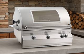 Fire Magic Aurora A790i in a concrete counter inside a brick alcove, hood closed, window and four knobs visible