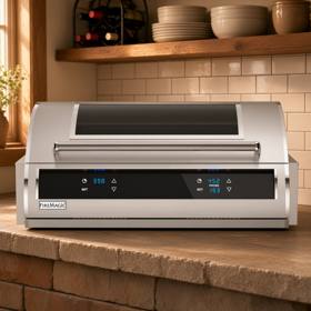 Fire Magic EL500i built into a stone counter, hood closed with a dark glass window and two lit touch control displays