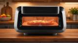 Frigidaire indoor pizza oven on a wooden kitchen counter, a pizza baking behind the glowing window