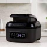 Black George Foreman Beyond Grill closed on a pale kitchen counter, control panel glowing below the hood