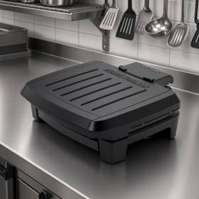 George Foreman Submersible contact grill closed on a stainless prep bench, black ribbed lid, control probe at the rear