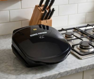 George Foreman GR10B closed on a marble worktop beside a gas hob, amber lamp lit on its lid