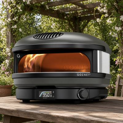 Gozney Arc gas pizza oven on a wooden table under a pergola, flame lit and dial showing 950