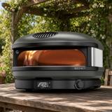 Gozney Arc XL on a wooden table under a pergola, flame lit and display reading 450