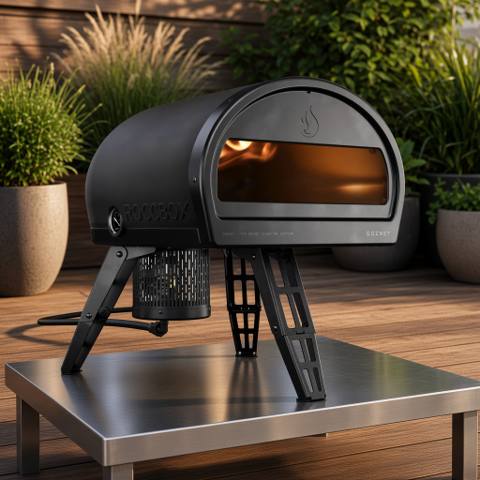 Gozney Roccbox on its folding legs on a steel outdoor table, gas burner attached at the side