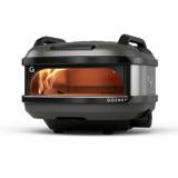 Gozney Tread portable gas pizza oven in off black with roof handles, a flame curling across the dome
