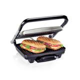 Hamilton Beach 25410MN panini press with its stainless lid raised, two pressed paninis on the ribbed lower plate