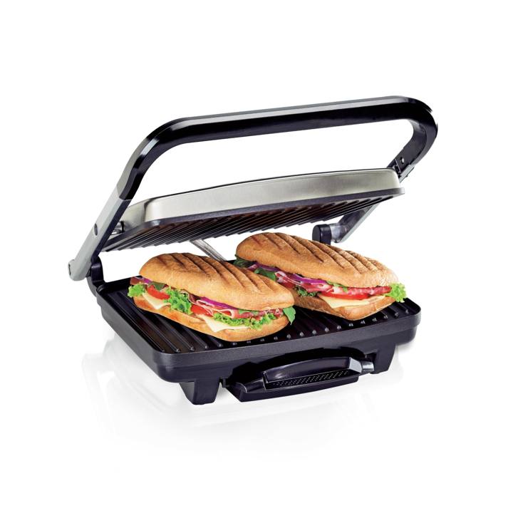 Hamilton Beach 25410MN panini press with its stainless lid raised, two pressed paninis on the ribbed lower plate