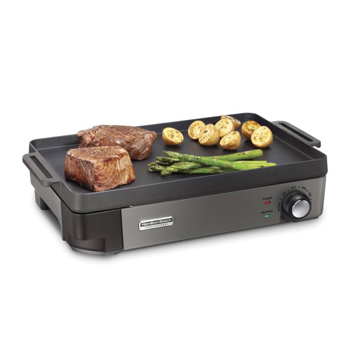 Hamilton Beach 38560 on a plain background, steak, potatoes and asparagus on its flat cast iron cooktop