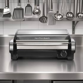 Hamilton Beach 25360 searing grill on a plain background, stainless hood raised above the ribbed nonstick plate