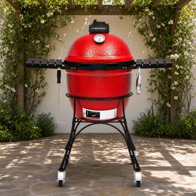 Red Kamado Joe Classic I on its black wheeled cart with slatted side shelves, under a pergola on a stone patio