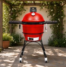 Red ceramic Kamado Joe Classic II on a black rolling stand under a wooden pergola, side shelves out, lid closed