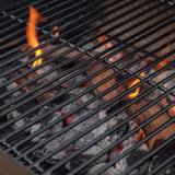 Close-up of the porcelain enameled wire cooking grid with lit charcoal and small flames burning underneath