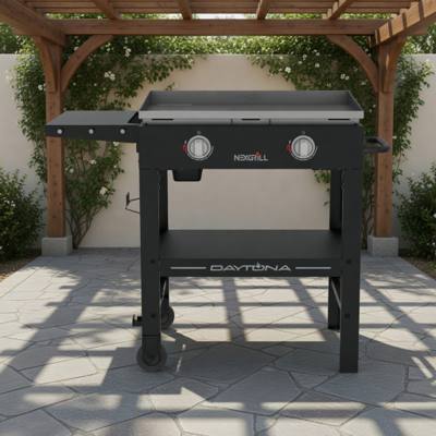 Nexgrill Daytona 28 inch gas griddle on a stone patio under a pergola, flat steel plate, two knobs, one side shelf