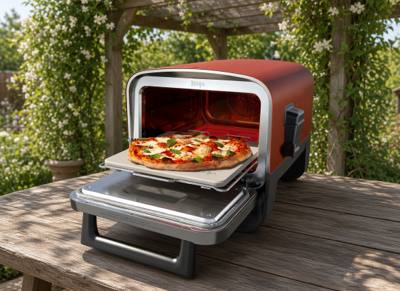 Ninja Woodfire outdoor pizza oven on a wooden garden table, door open with a pizza on the stone
