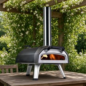 Ooni Karu 2 with its chimney and folding legs on a wooden garden table under a pergola