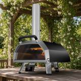 Ooni Karu 2 Pro with chimney and glass door on a wooden table under a pergola