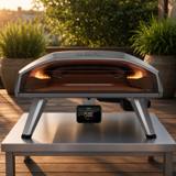 Ooni Koda 2 Pro with its temperature hub on a steel outdoor table on a timber deck in low evening sun